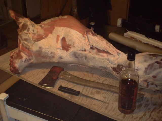 Tools for cutting meat: a knife, an axe and a bottle of rum